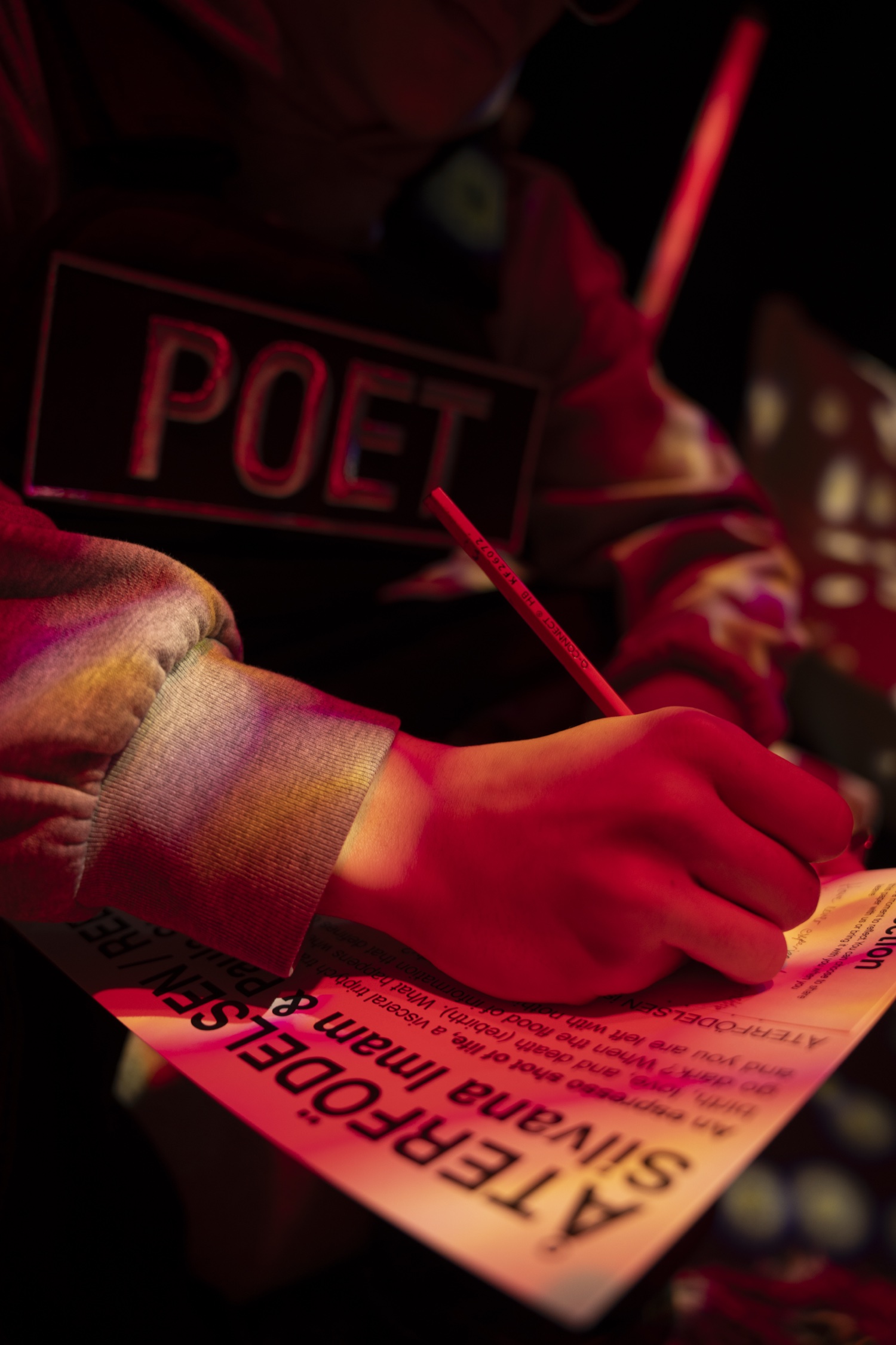 A visitor in the POET vest writing a reflection card in red light